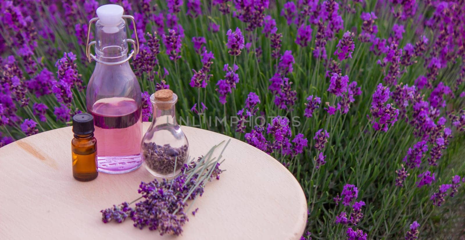 jars with lavender oil, lavender flowers, on the background of a lavender field. Selective focus