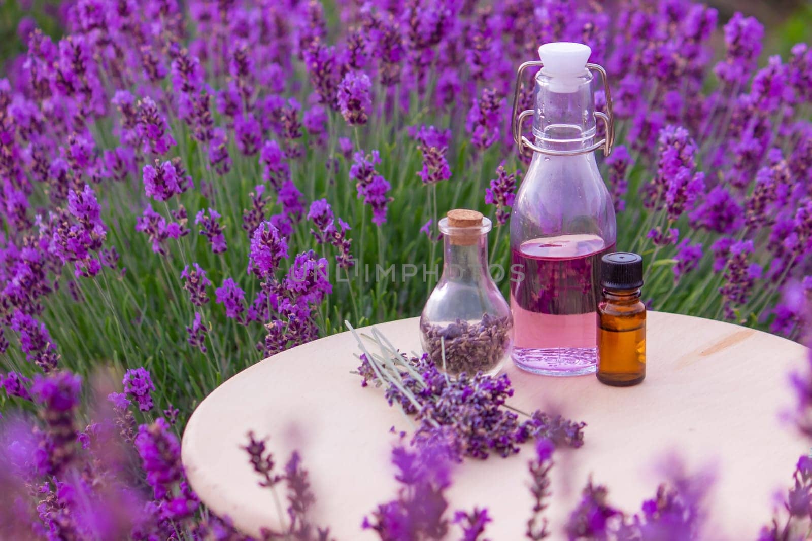 jars with lavender oil, lavender flowers, on the background of a lavender field. Selective focus