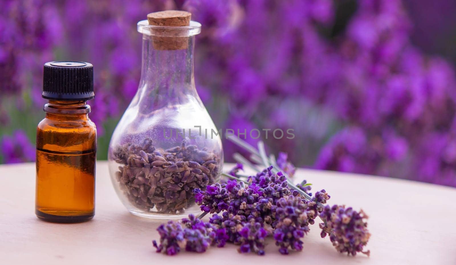 jars with lavender oil, lavender flowers, on the background of a lavender field. Selective focus