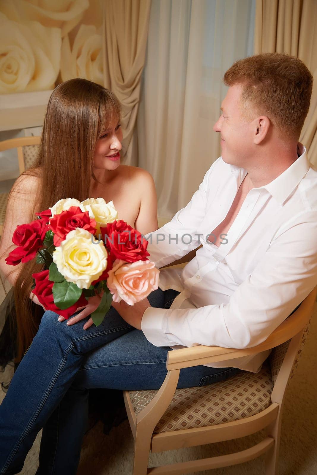 An adult couple of newlyweds in beautiful dress in a hotel room after the wedding. A guy and a girl, a man and a woman in a beautiful room. The concept of love and care by keleny