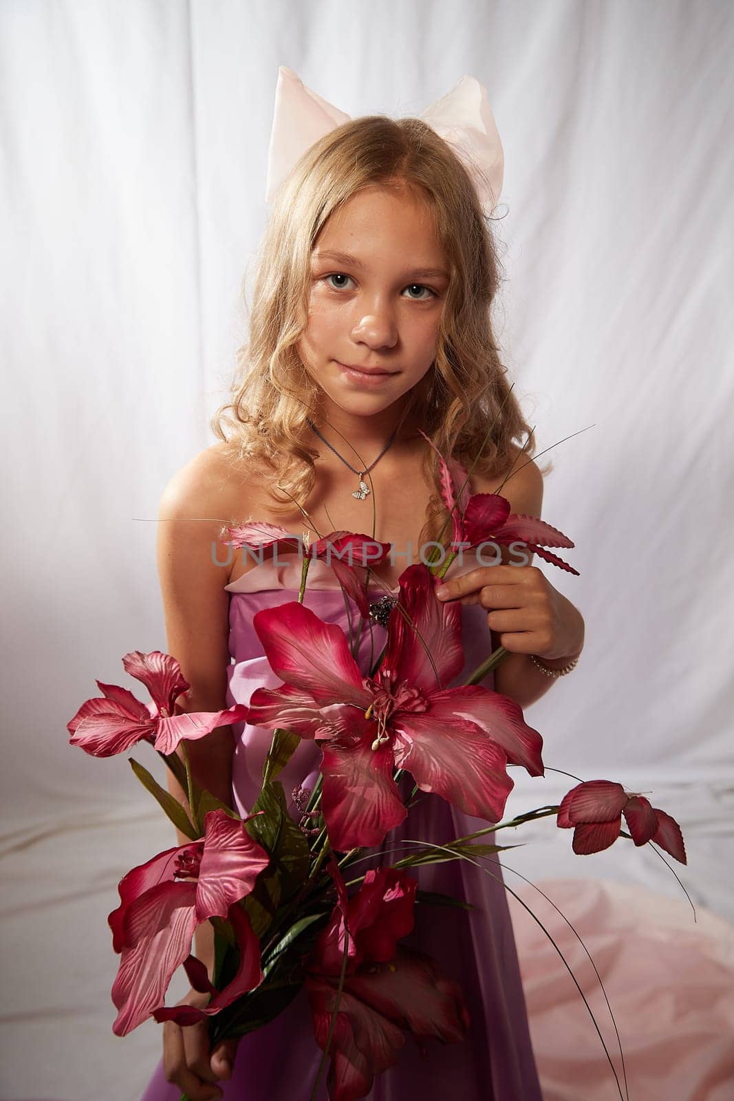 Portrait of cute kid girl posing in pink beautiful dress on white background. Model in studio looking as gentle magic princess from fairy taly having photo shoot on white background