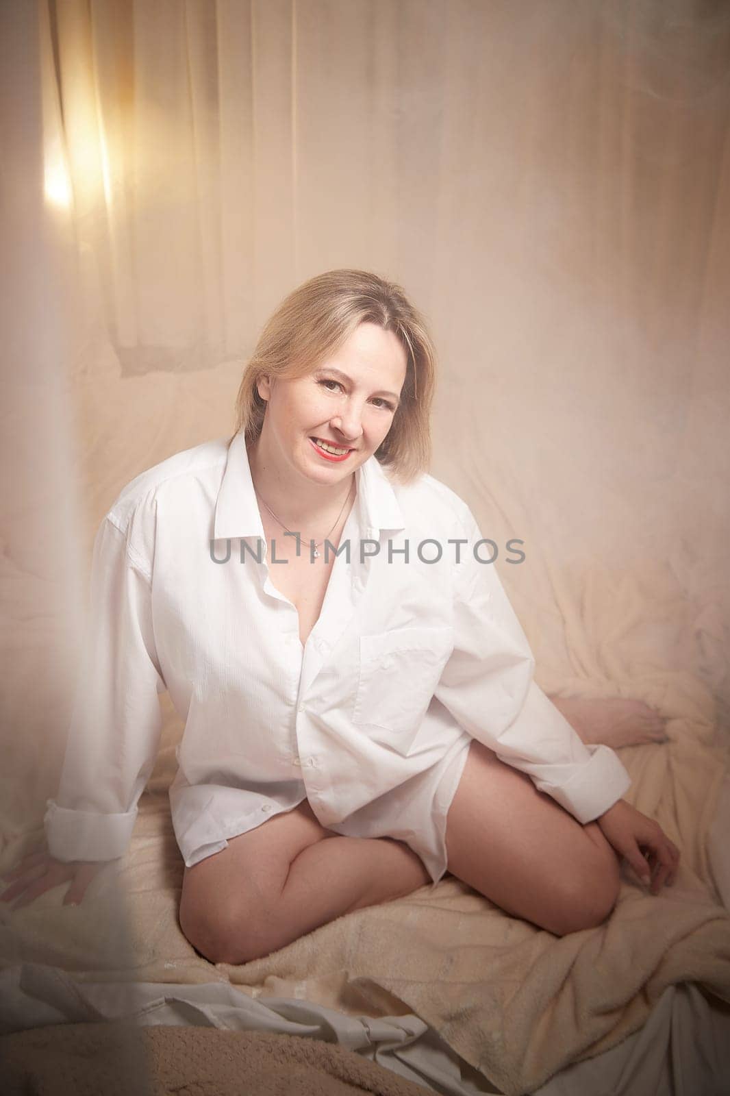 Portrait of sexual body positive adult lady woman in an intimate in tender space indoors in a bedroom. Plump girl poses in black underwear and white shirt during boudoir style photo shoot by keleny