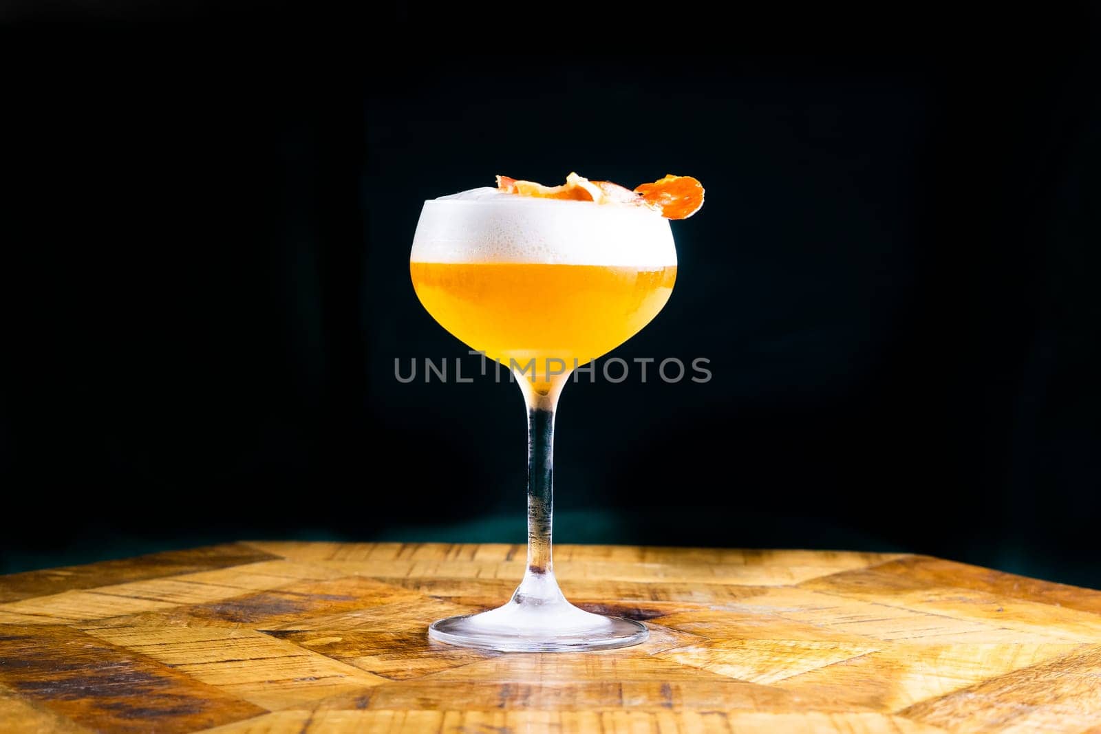 Stemmed cocktail glass with alcoholic drink, closeup isolated on black. Template design