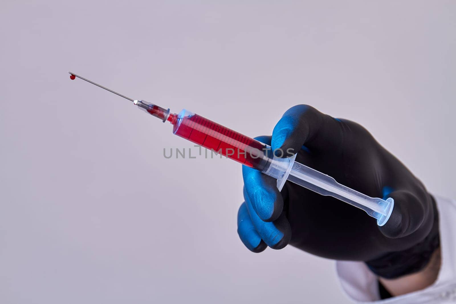 Close up hand with glove holding syringe with blood. Isolated on white.