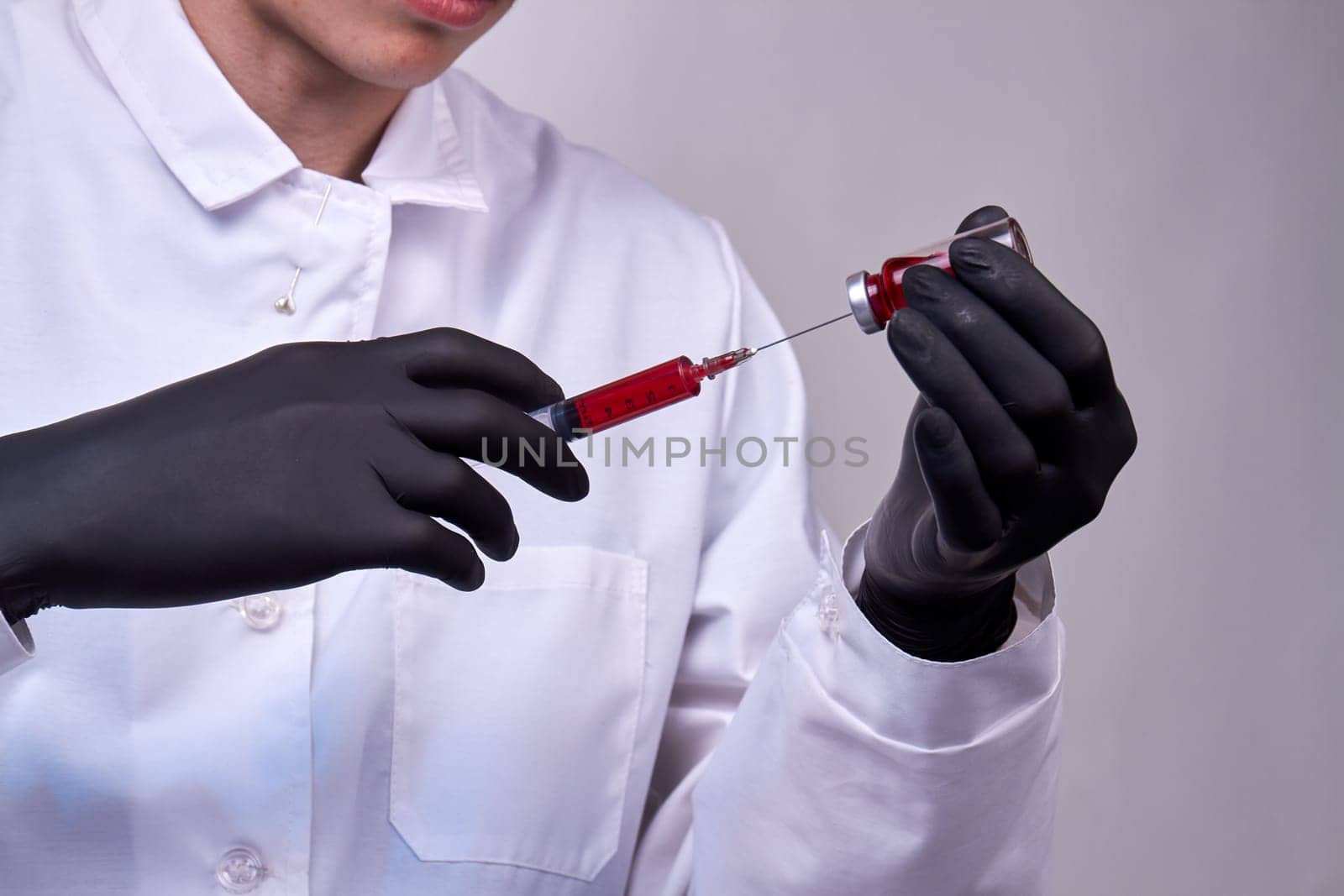 Doctor with black glove filling syringe with medication. Vaccination and immunization.