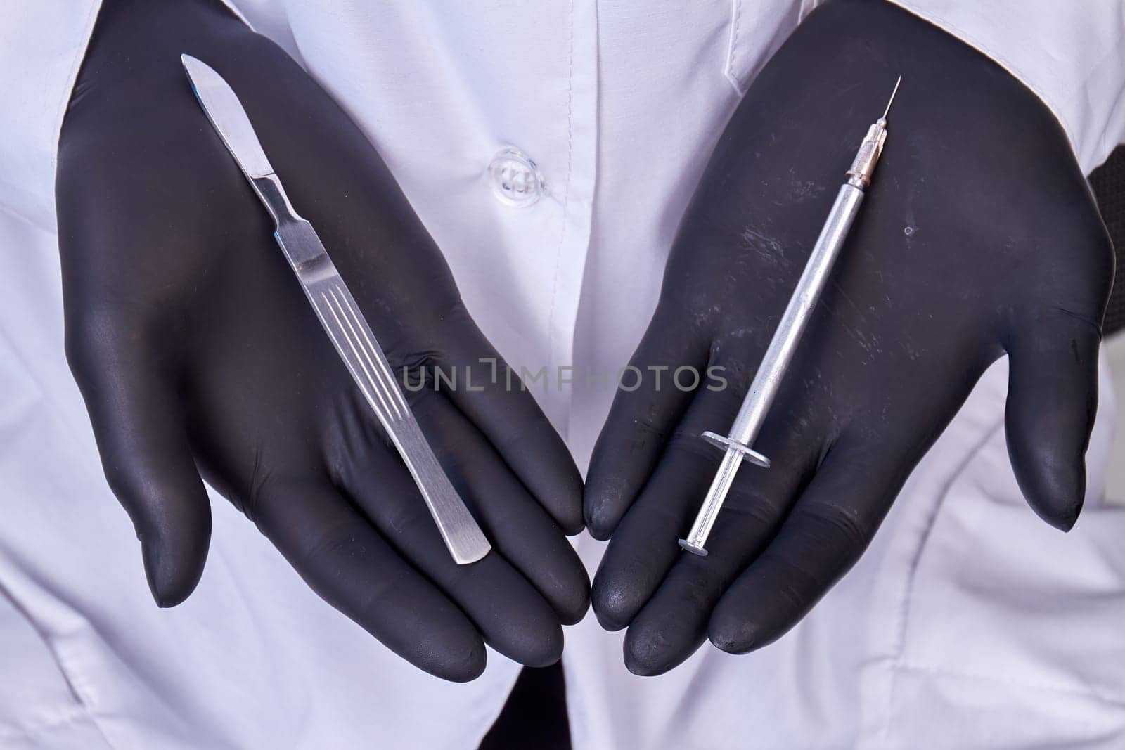 Close up doctors hands in gloves holding tools for cosmetic surgery. Scalpel and syringe.