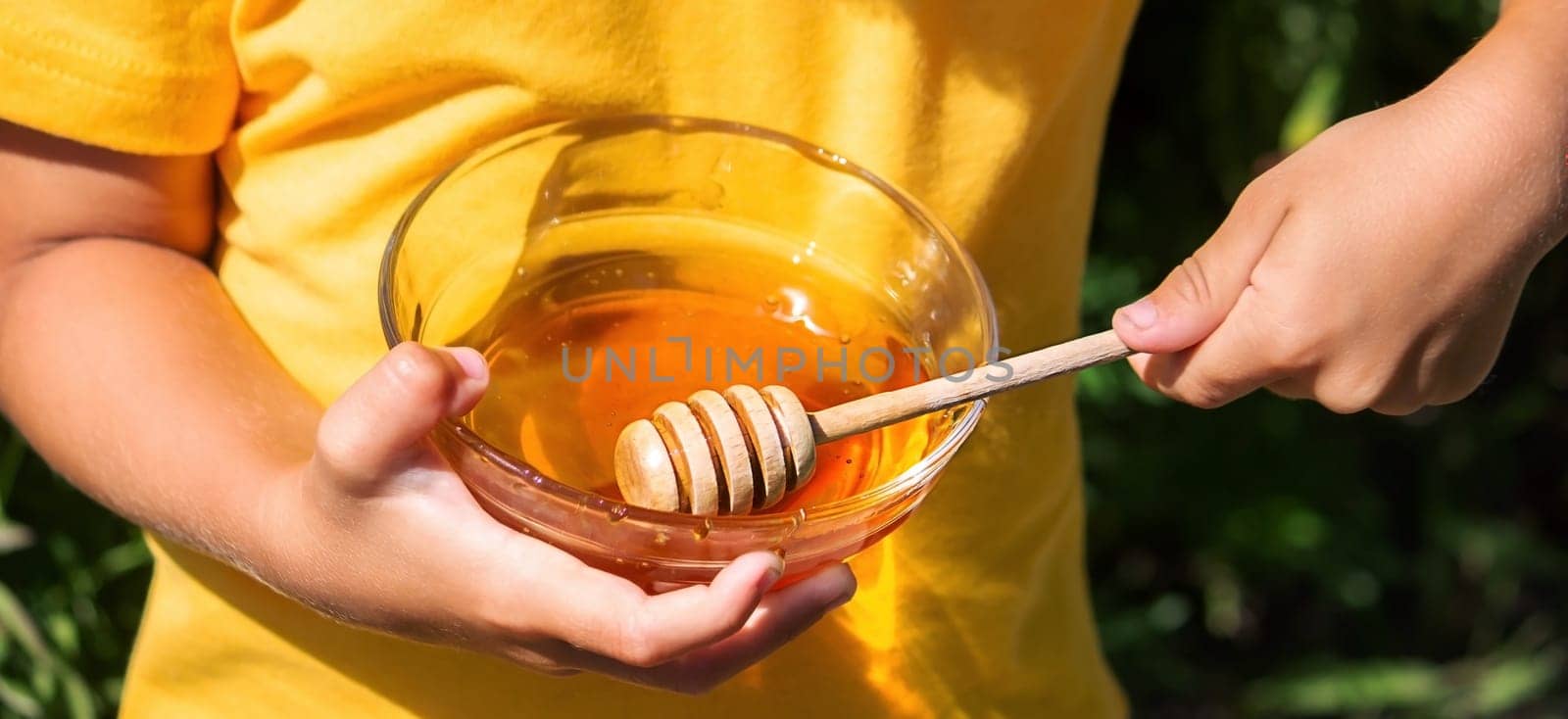a child eats honey in the garden from a transparent bowl. nature selective focus