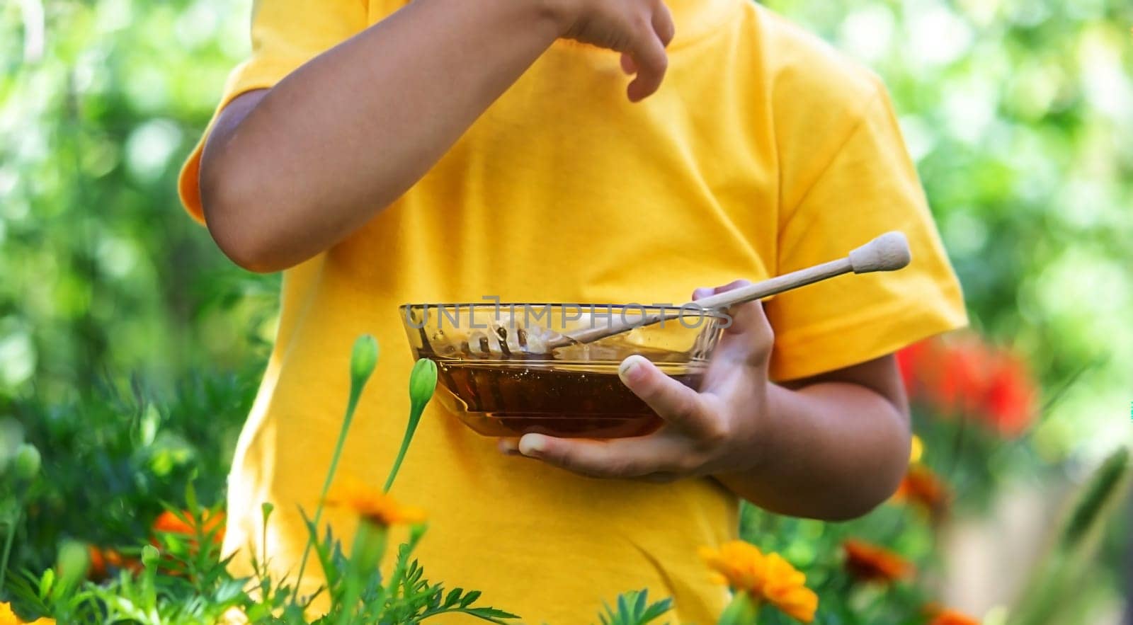 a child eats honey in the garden from a transparent bowl. nature selective focus