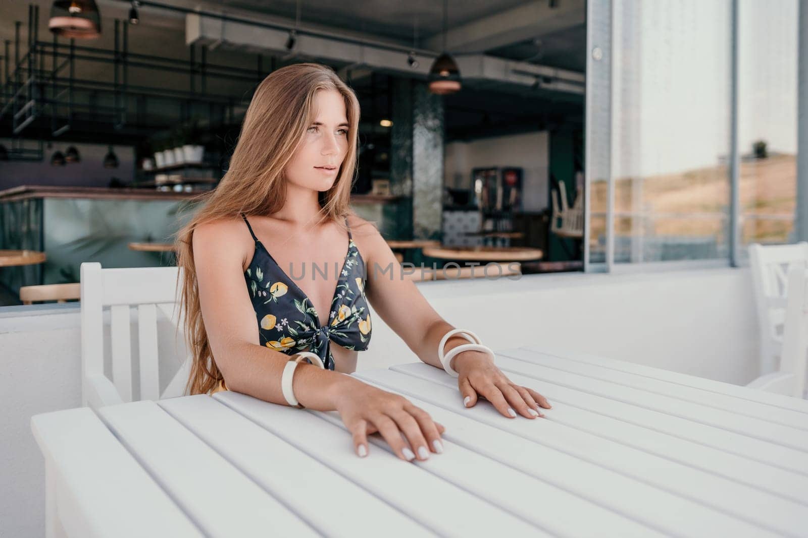 Happy woman portrait in cafe. Boho chic fashion style. Outdoor photo of young happy woman with long hair, sunny weather outdoors sitting in modern cafe
