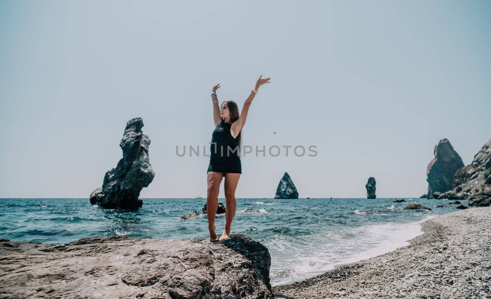 Woman summer travel sea. Happy tourist in hat enjoy taking picture outdoors for memories. Woman traveler posing on the beach at sea surrounded by volcanic mountains, sharing travel adventure journey by panophotograph