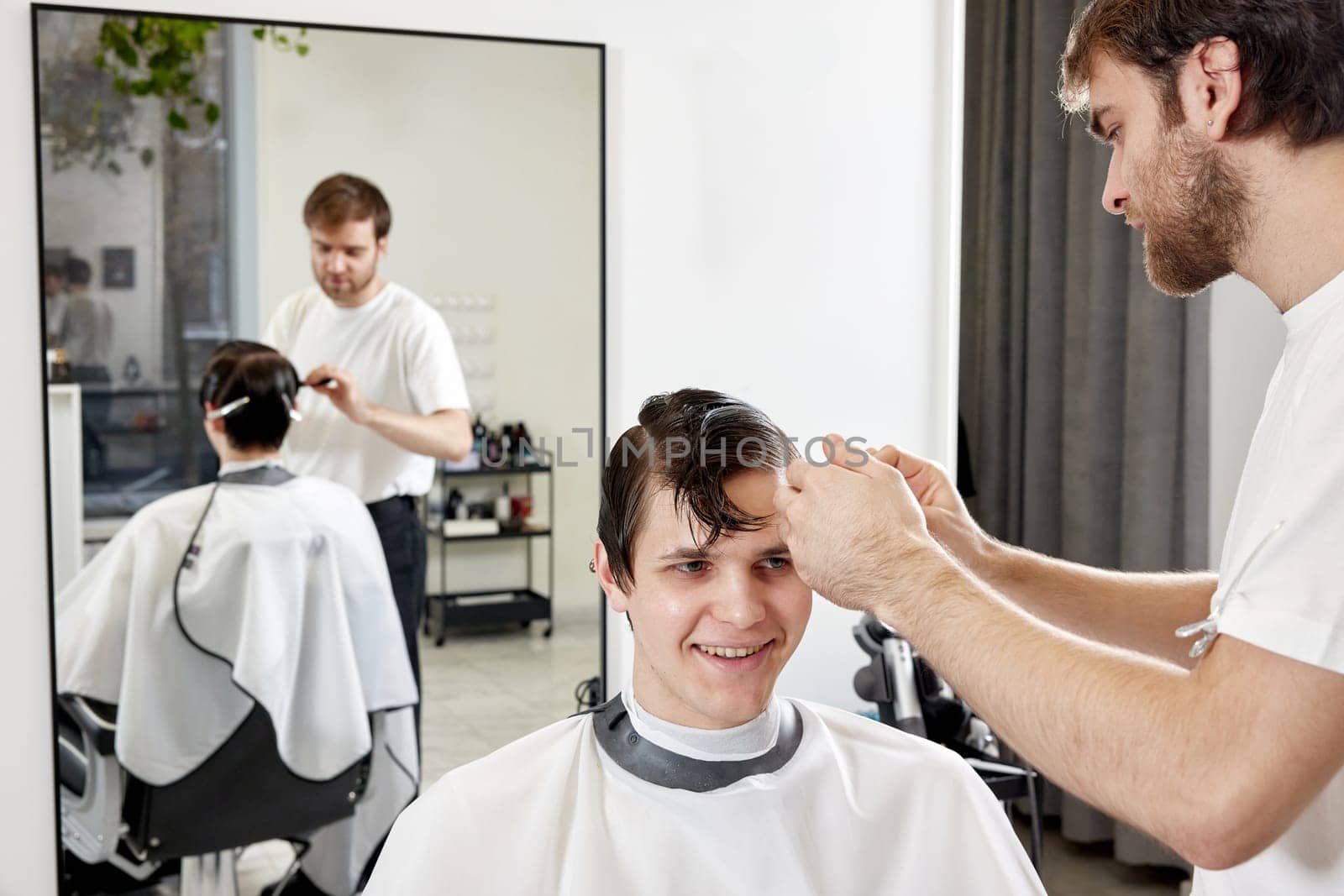 Professional barber during work with man client by erstudio