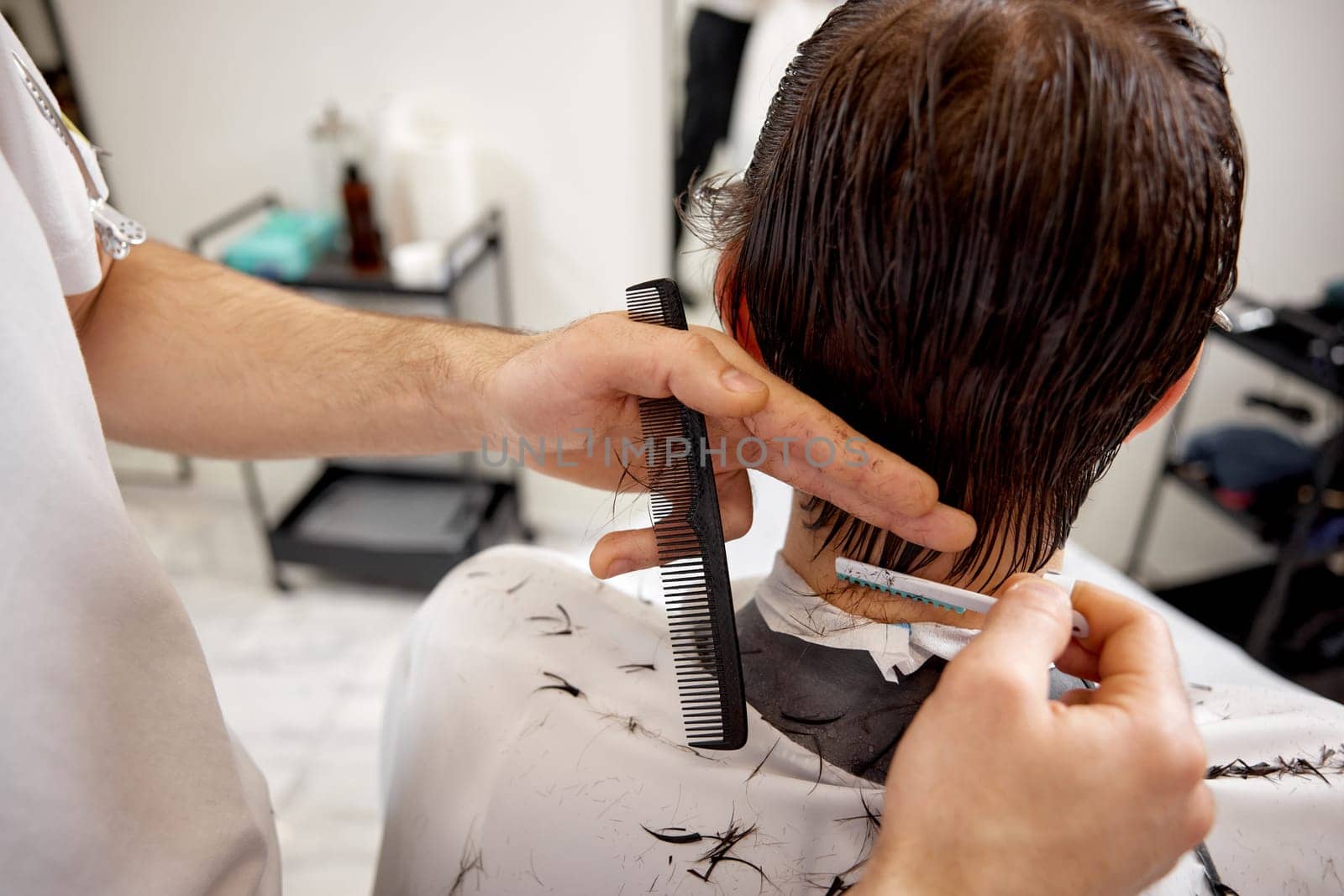 hairdresser does haircut for caucasian man in barber shop. close-up