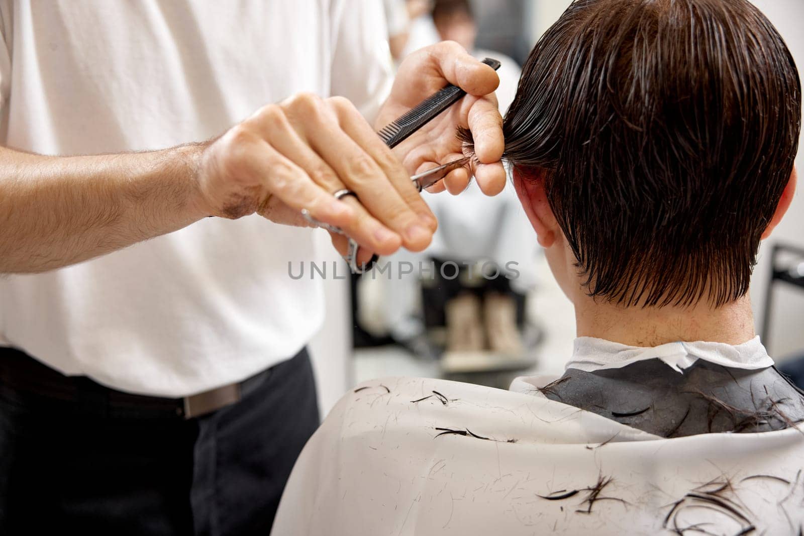 hairdresser does haircut for caucasian man in barber shop. close-up