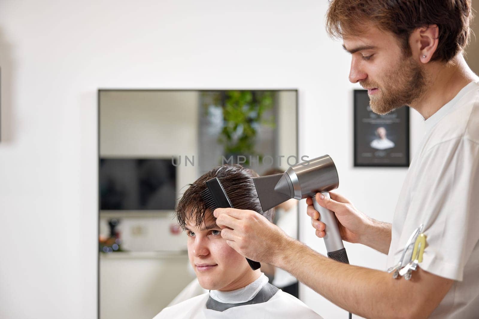 Professional hairdresser using hair dryer and comb in barber shop. Haircut in the barbershop.