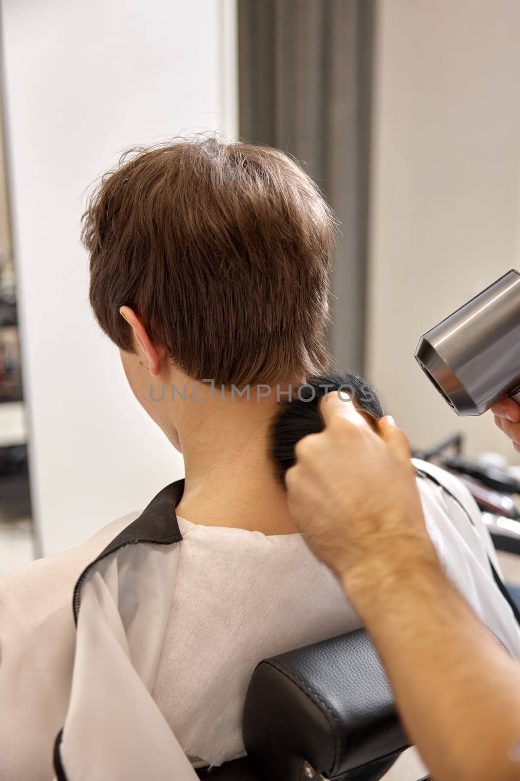 young caucasian man getting haircut by professional male hairstylist at barber shop.