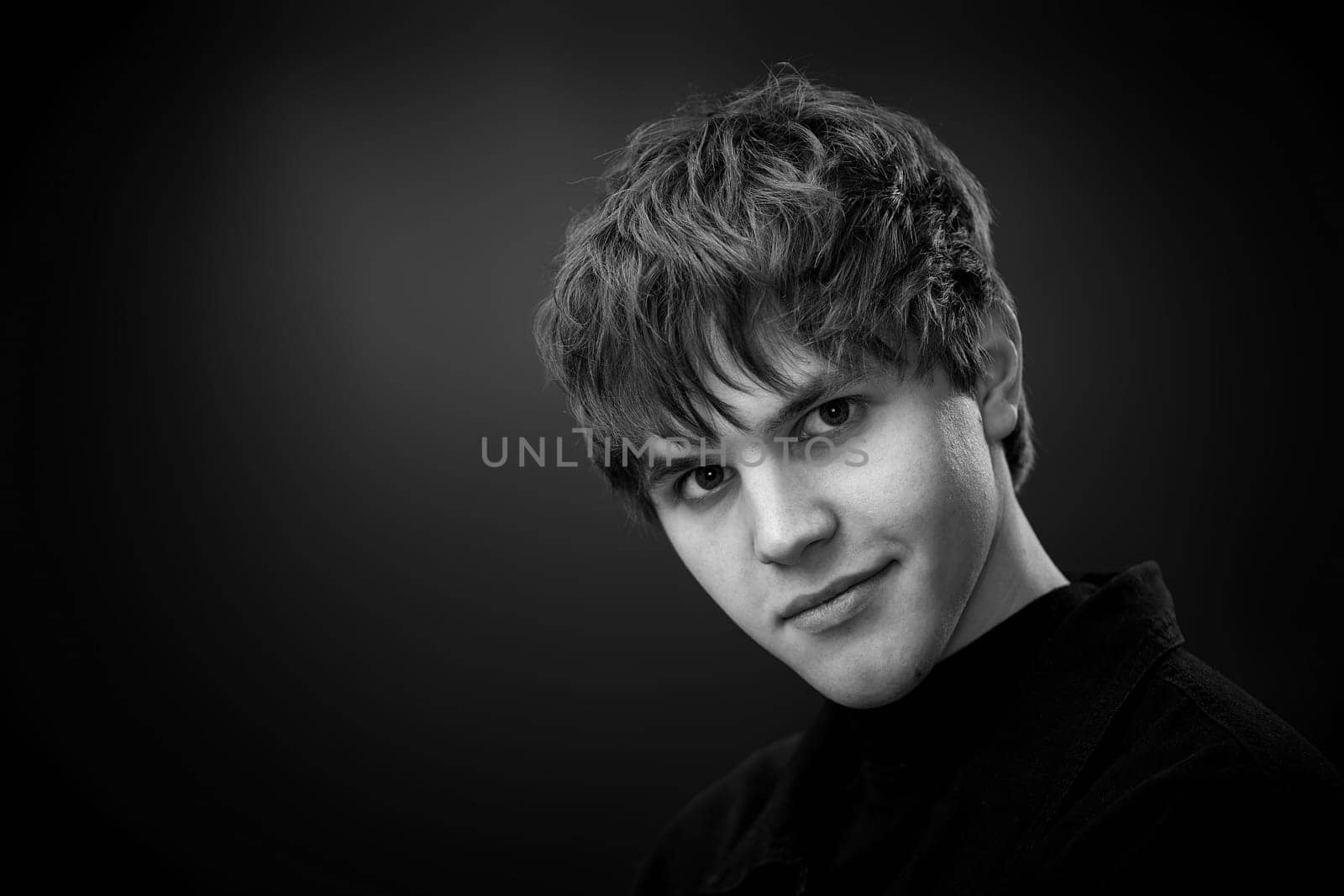 close-up portrait of positive handsome man looking at the camera on black background. black and white. copy space