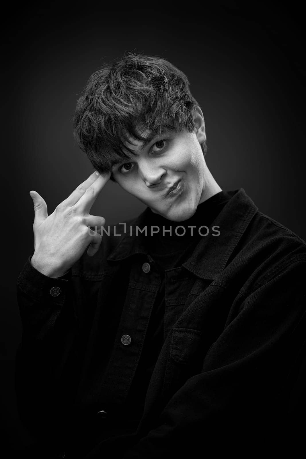 young man standing with finger gun pointed to head by erstudio