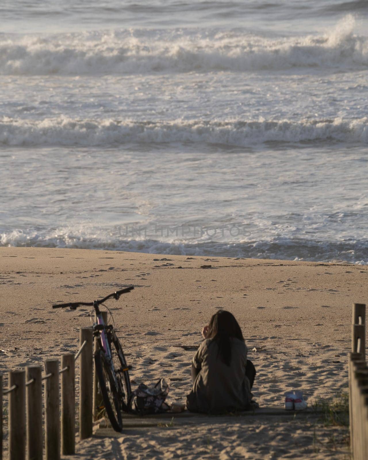Lonely young woman sitting in front of the sea waves to isolate from day to day tasks.