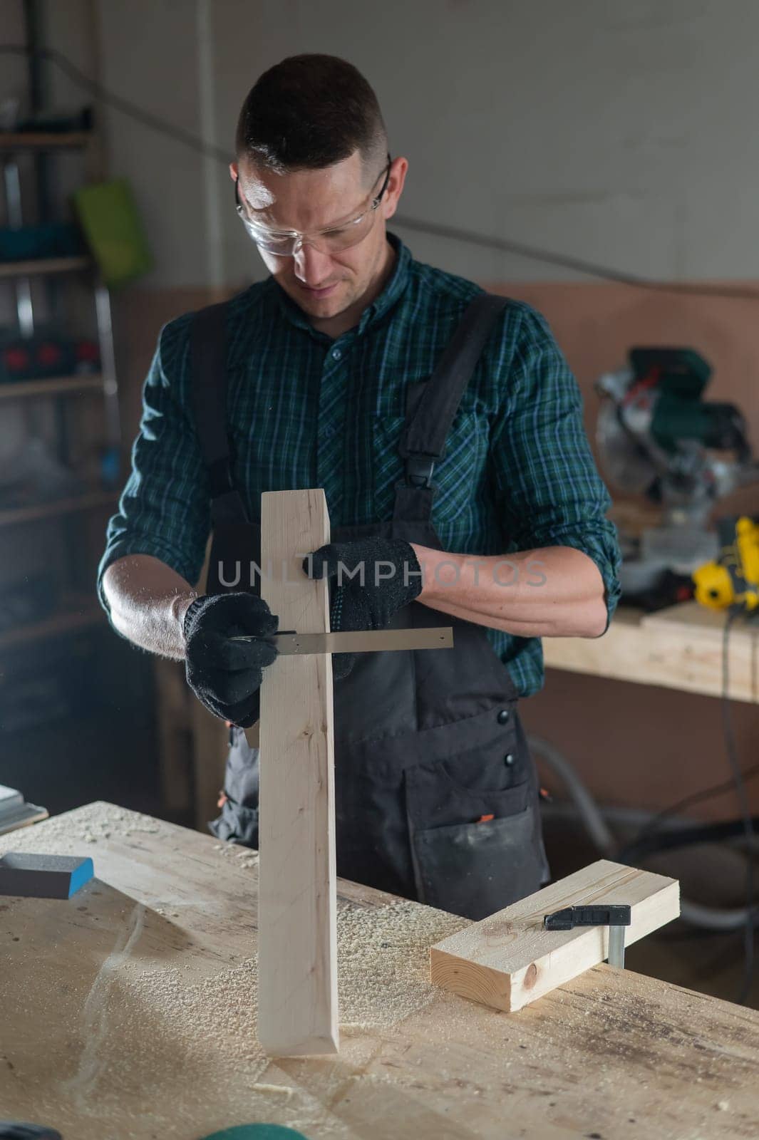 Carpenter measures a wooden board while working in a workshop