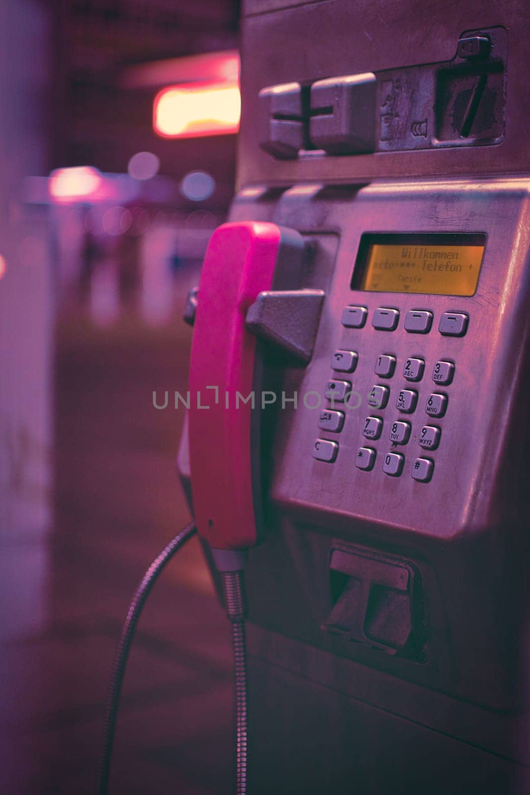 Vertical closeup shot of a public phone booth with pink handset in Duisburg, Germany