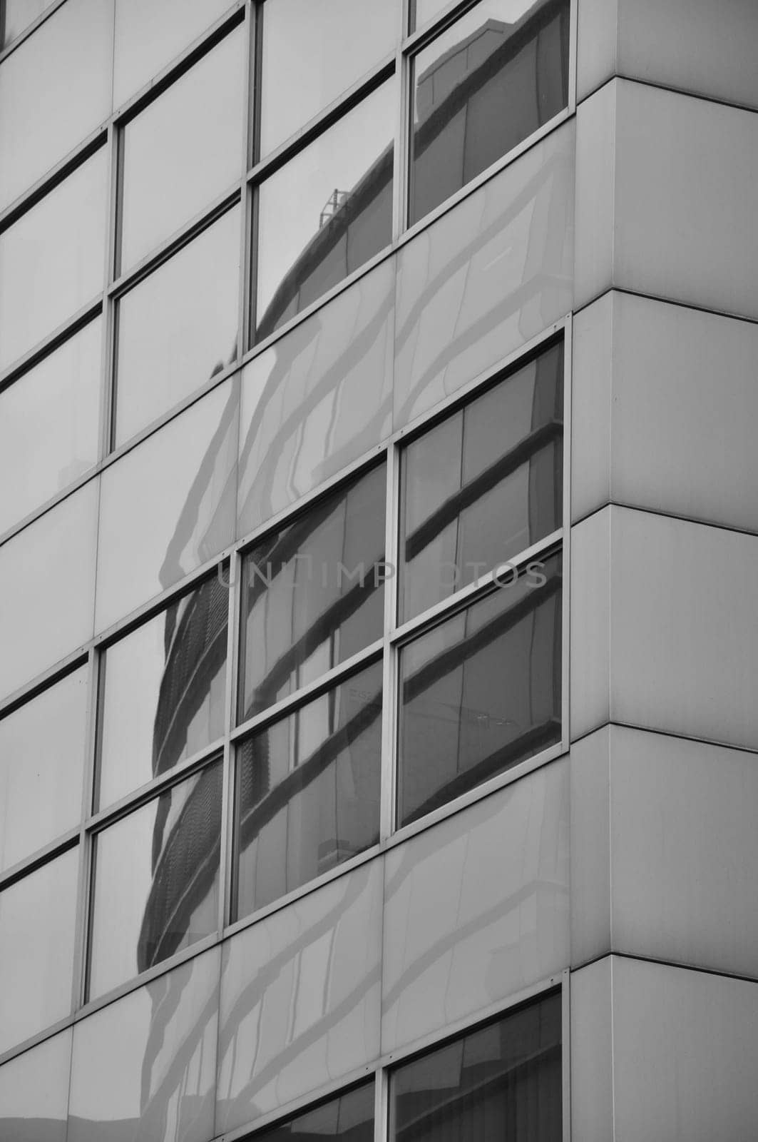 Vertical grayscale shot of buildings reflection in window pane in Media Harbor. Dusseldorf, Germany.