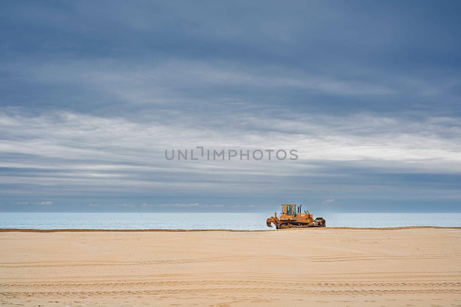 Morning beach scenery with tractor cleaning sand, getting beach ready for summer vacation. European travel. Italy.
