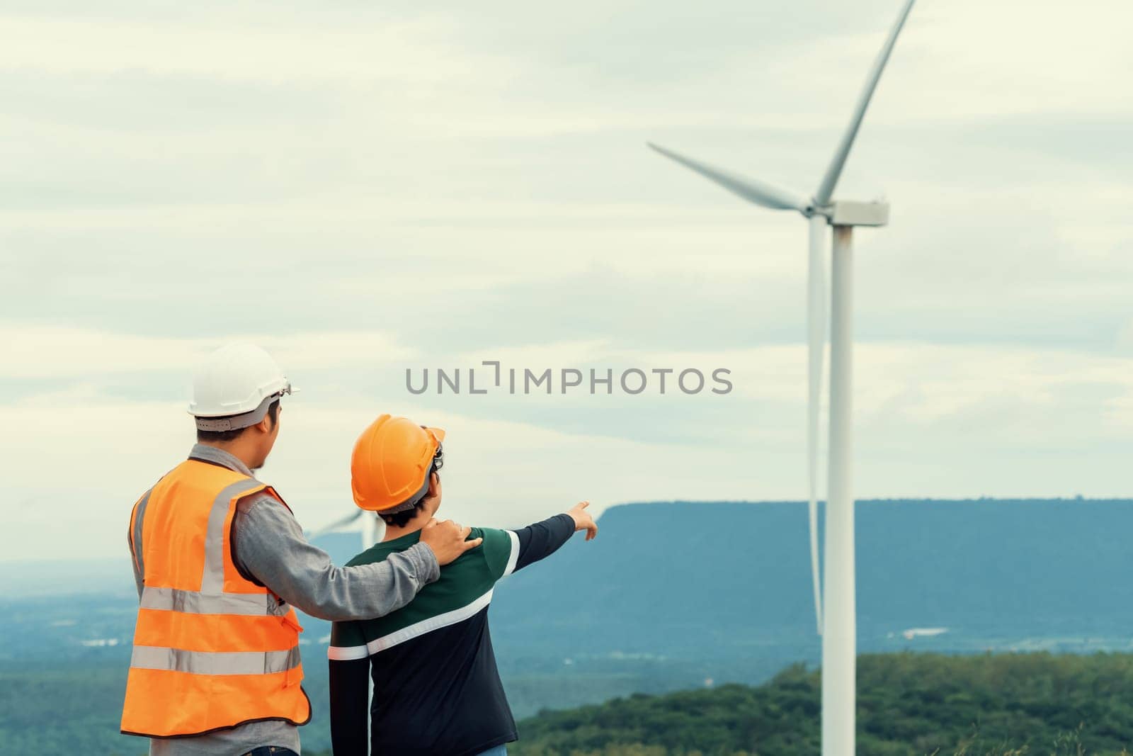 Engineer with his son on a wind farm atop a hill or mountain in the rural. Progressive ideal for the future production of renewable, sustainable energy. Energy generation from wind turbine.