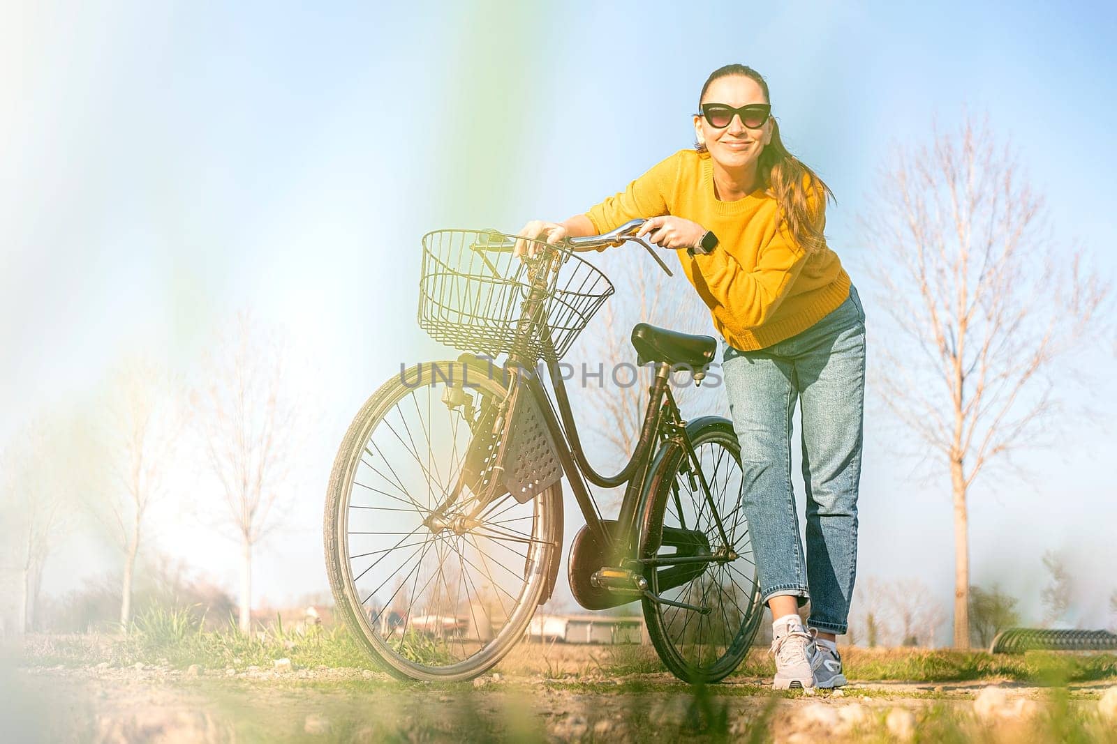 Beautiful young woman on bike in park in spring.