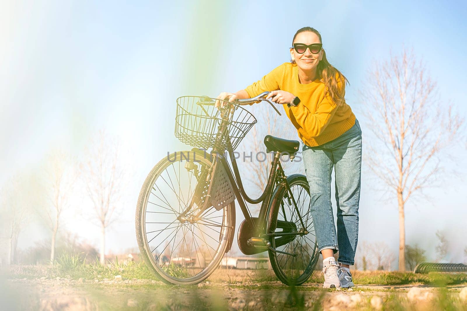 Beautiful young woman on bike in park in spring.