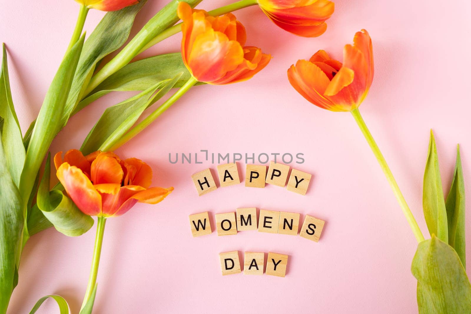 March 8, postcard. Happy Women's Day text sign with orange tulips on pink background. Stylish flat lay with flowers and text, greeting card. by sfinks
