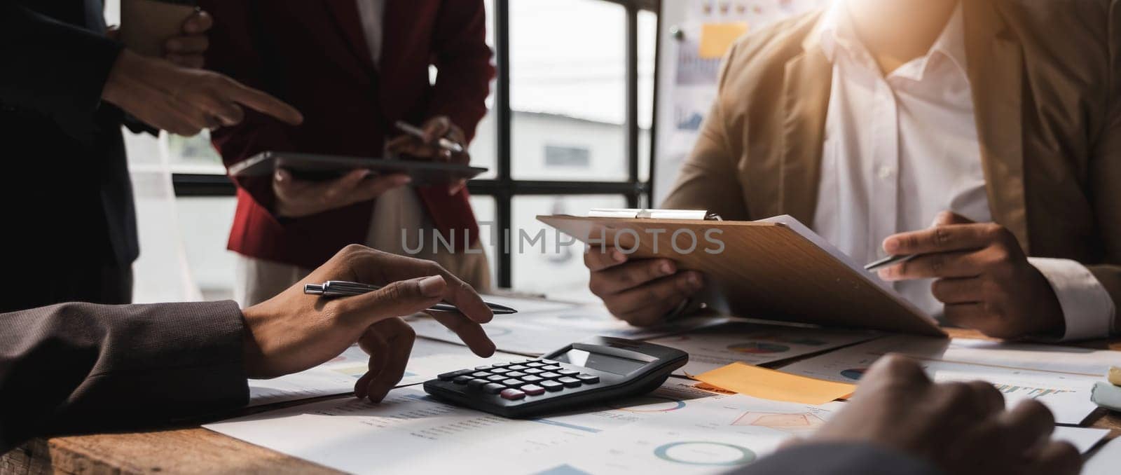 Business People Meeting using laptop computer,calculator,notebook,stock market chart paper for analysis Plans to improve quality next month. Conference Discussion Corporate Concept....