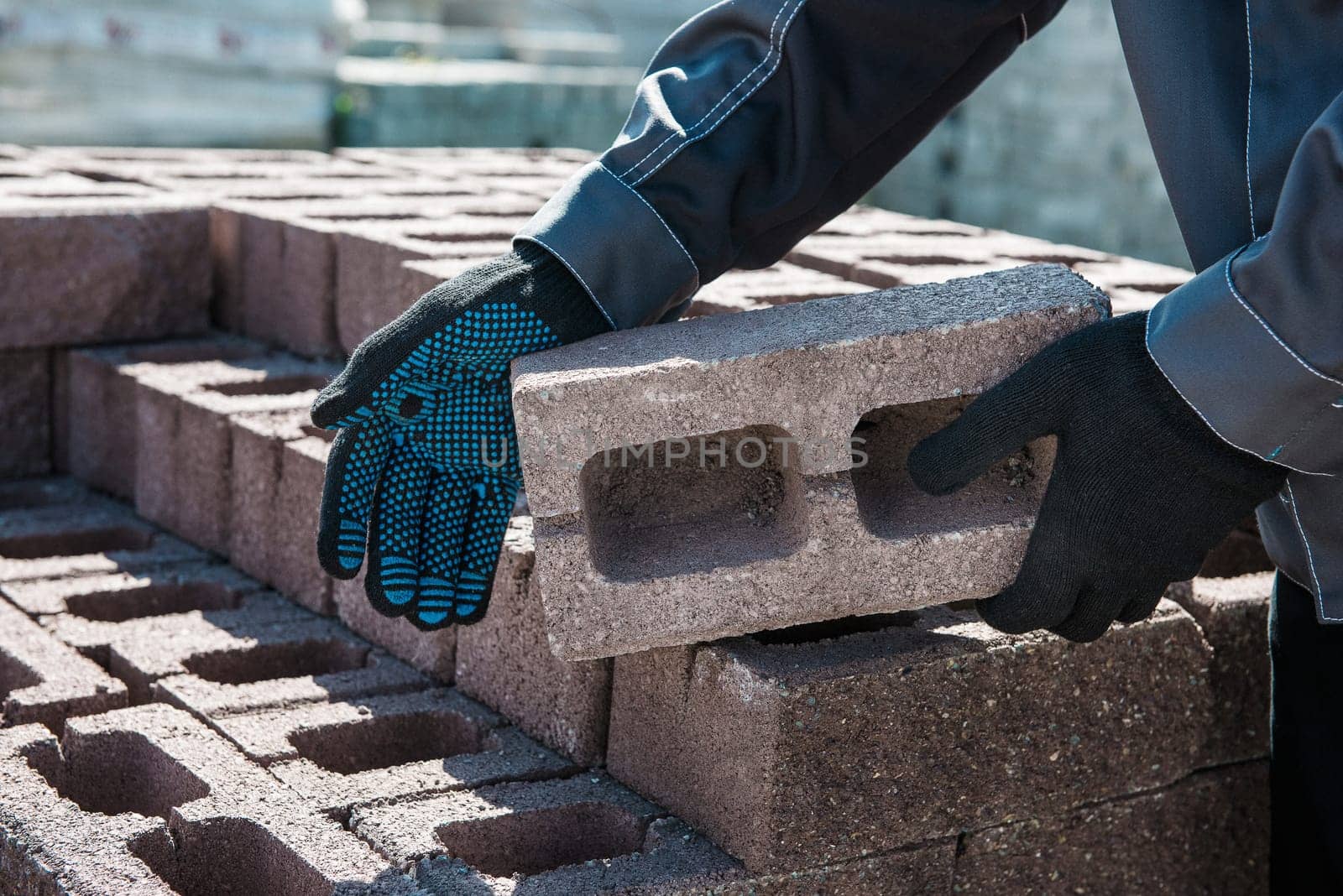Closeup of hand of a worker in a protective glove with brick. Constructing concept.