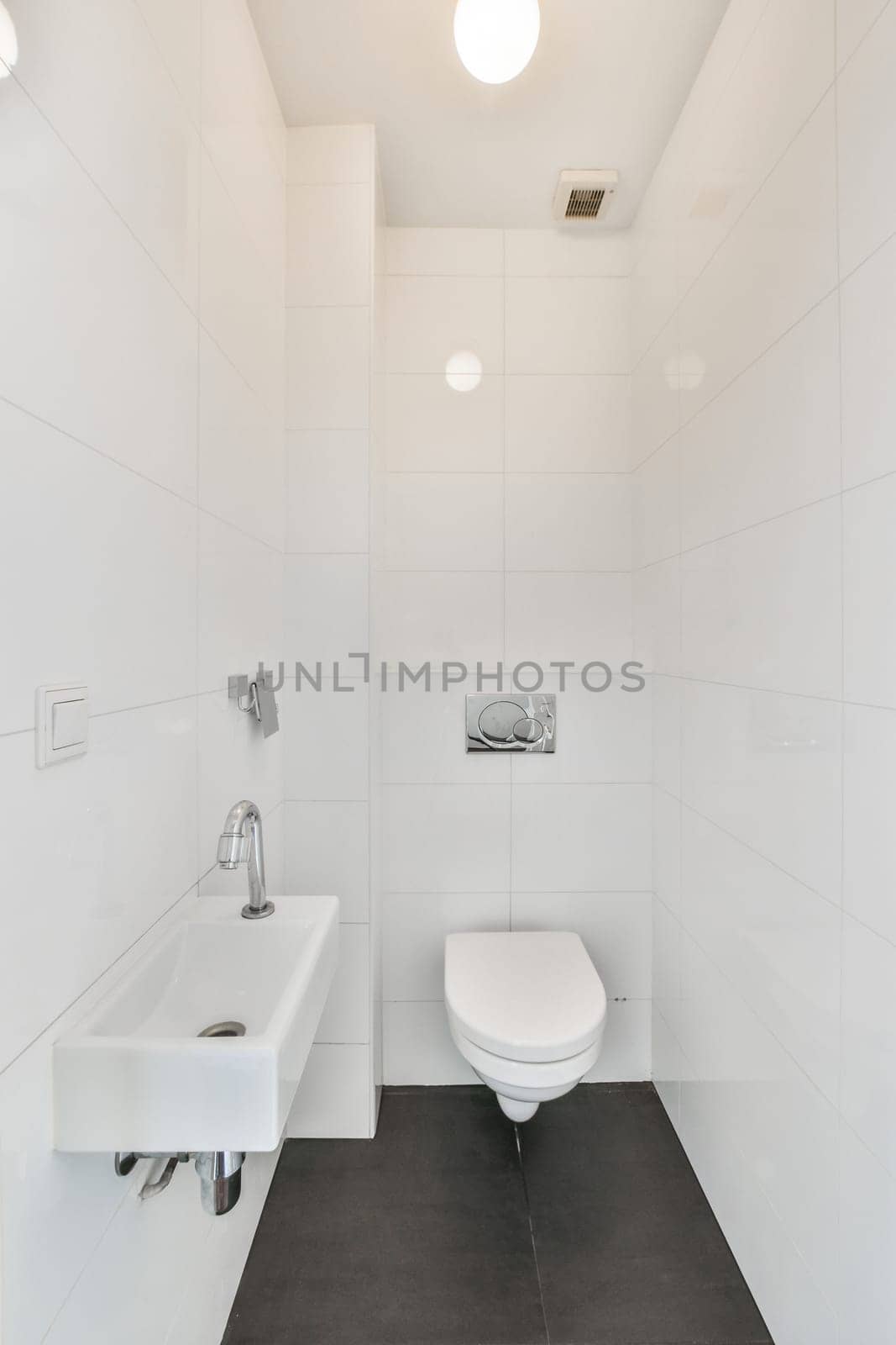 a white bathroom with black tile flooring and a toilet in the corner, there is a mirror on the wall