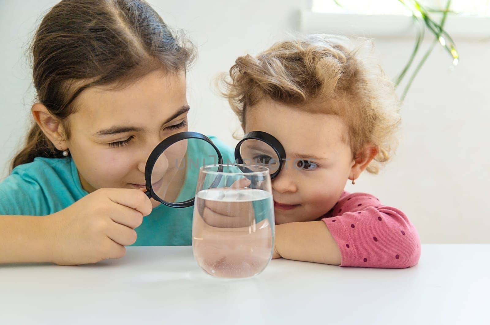 The child examines the water under a magnifying glass. Selective focus. by yanadjana