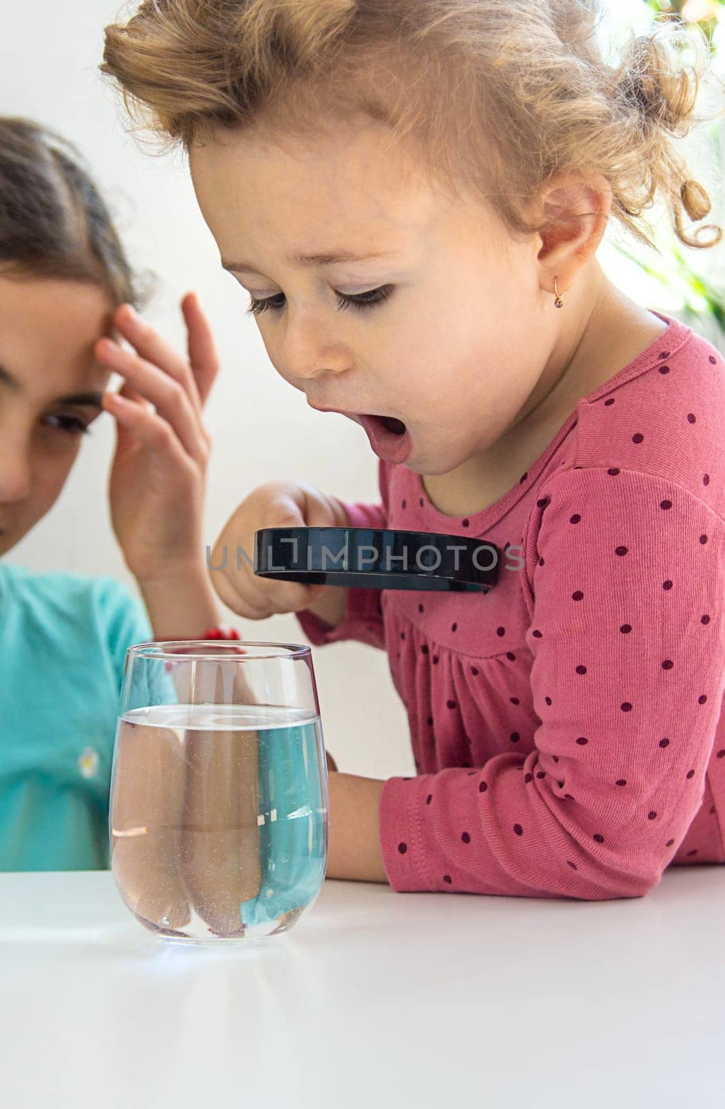 The child examines the water under a magnifying glass. Selective focus. Kid.