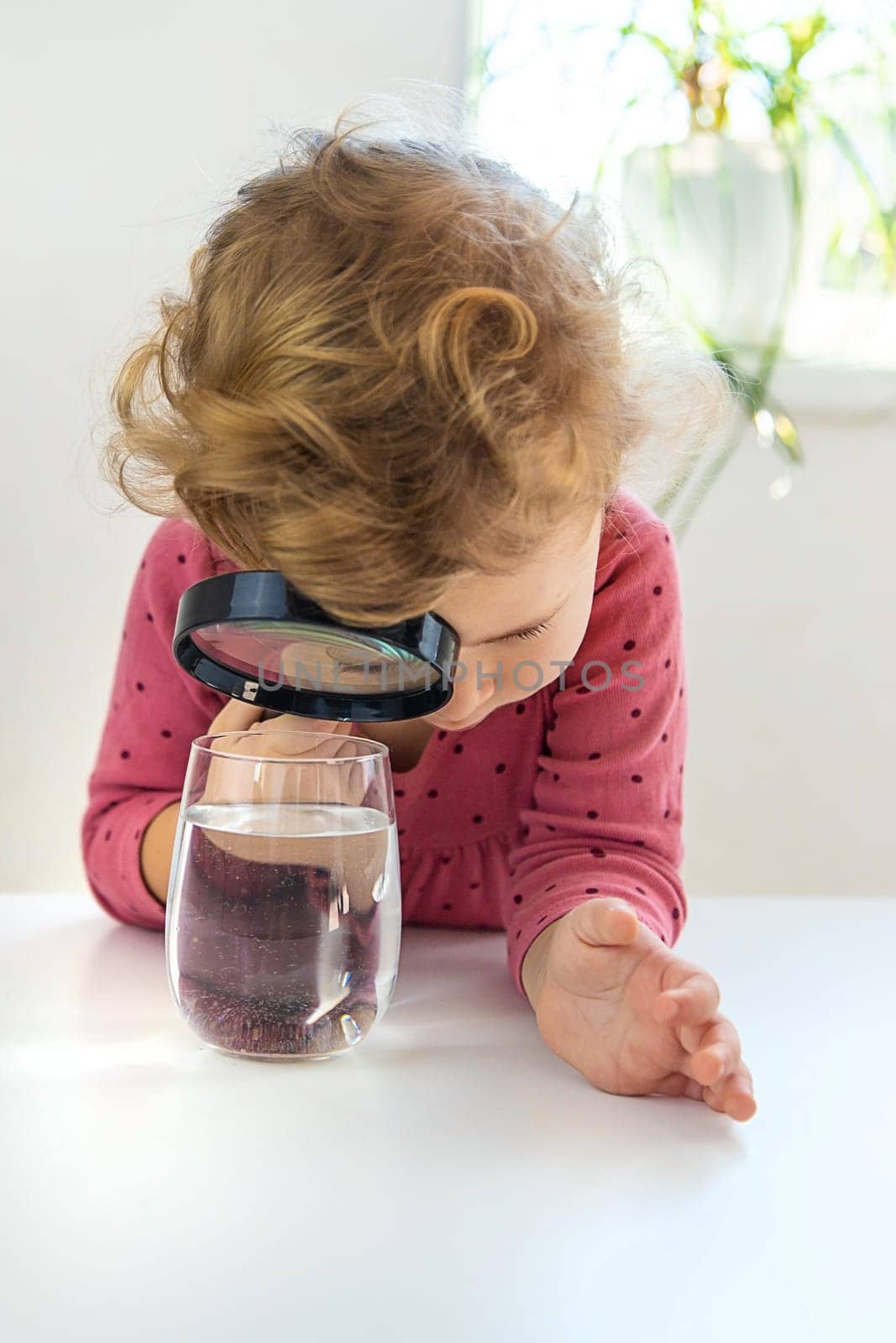 The child examines the water under a magnifying glass. Selective focus. Kid.