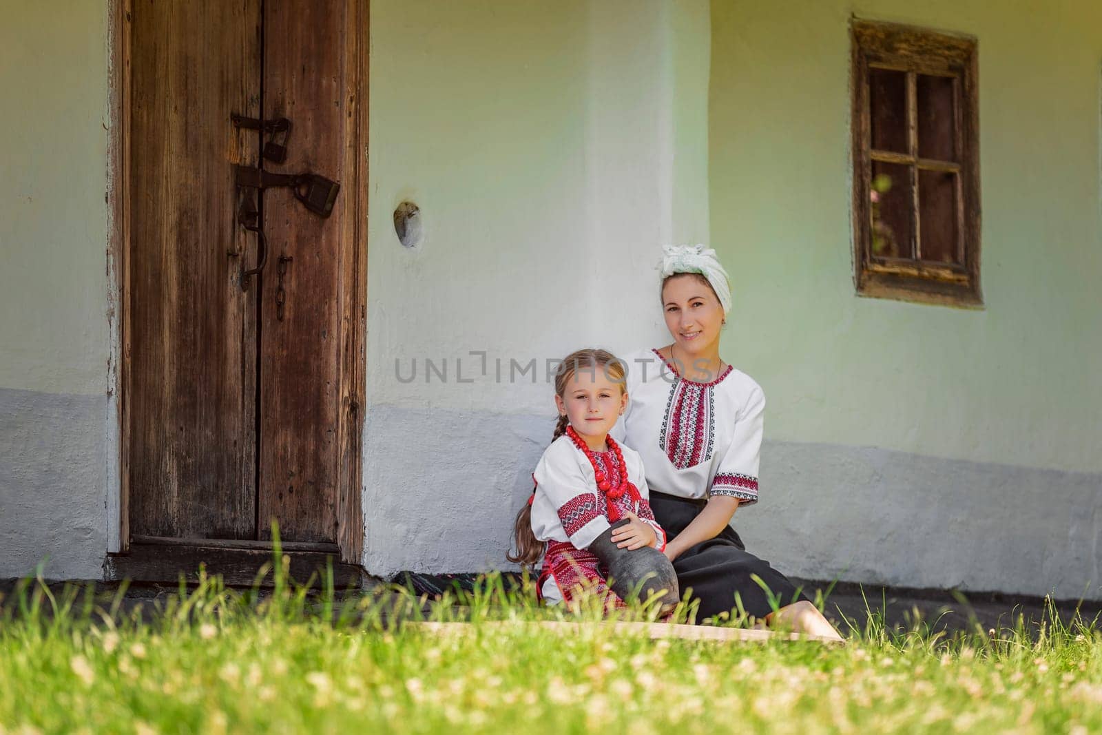 mother and daughter sitting near the house by zokov