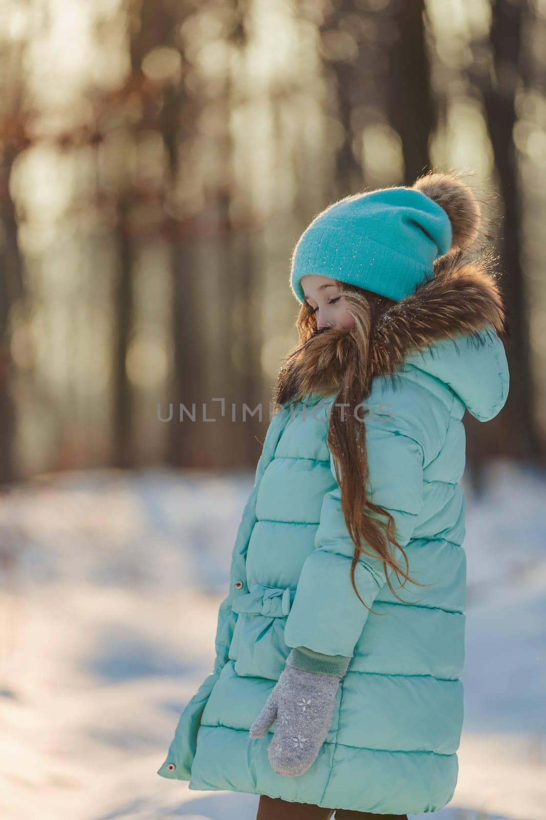 girl in a turquoise squat and a hat in a winter forest, shot vertically