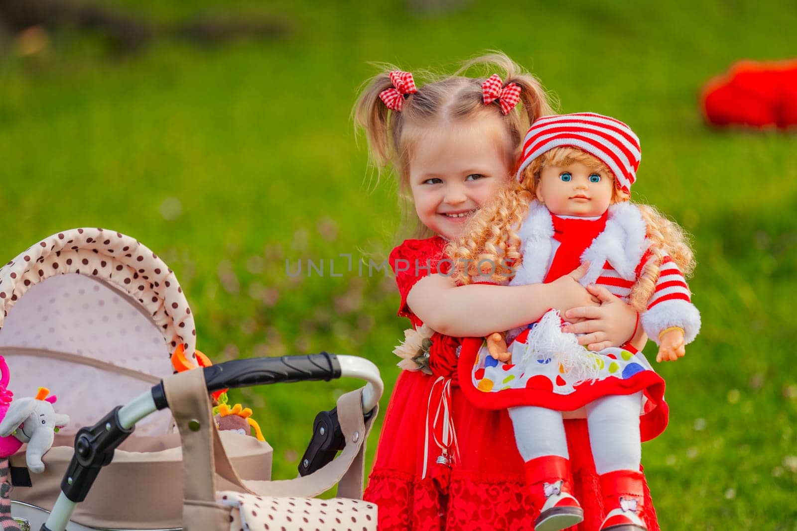 The girl plays with a doll in nature, holding her in her arms