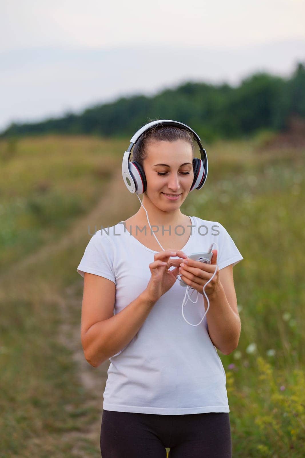 woman in headphones outdoors listening to music using phone