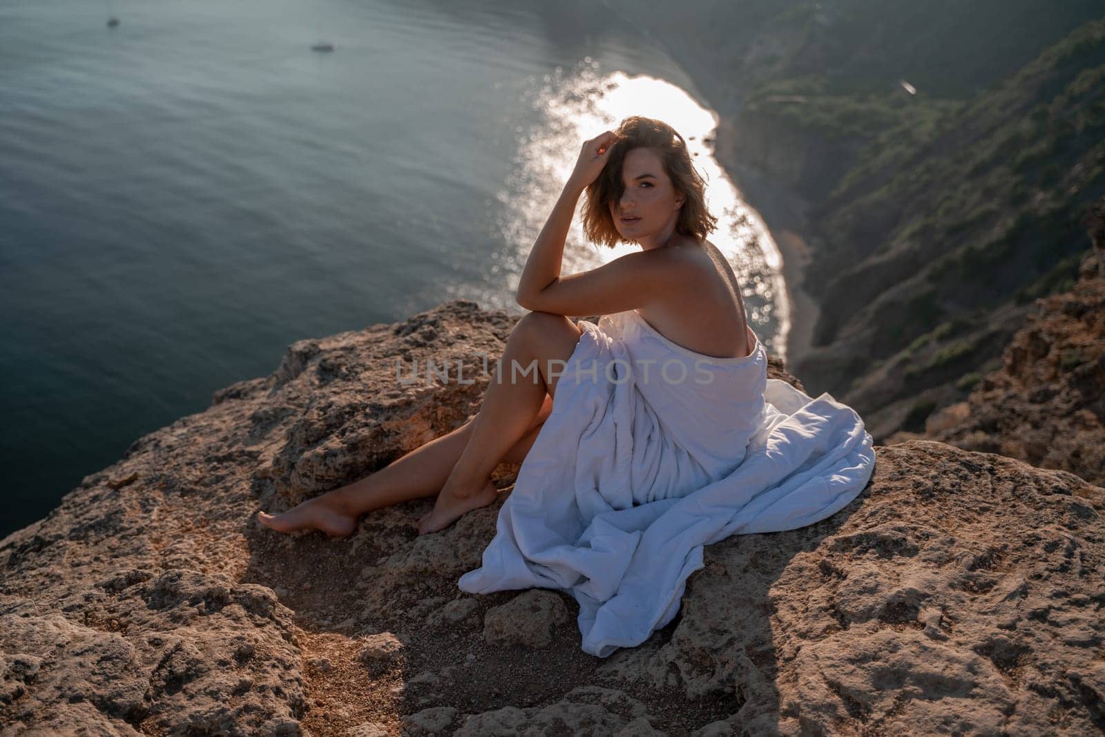 Woman wake up in bed wuth duvet and pillow over nature sea background outdoors. Back view. Good morning. Freedom concept