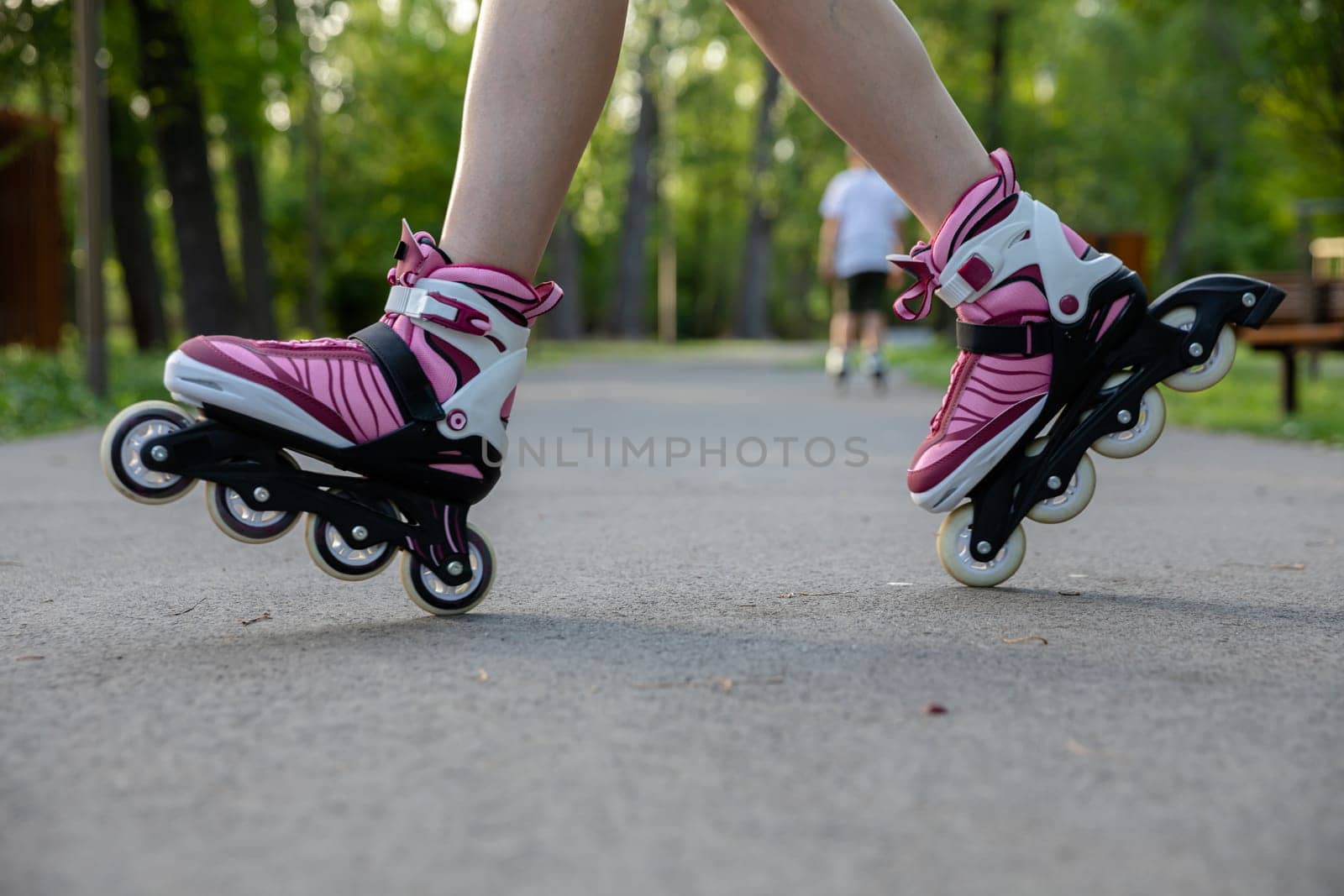 Learning to do tricks on roller skates. A city park suitable for sports. Playing sports outdoors. Active relaxation in nature.