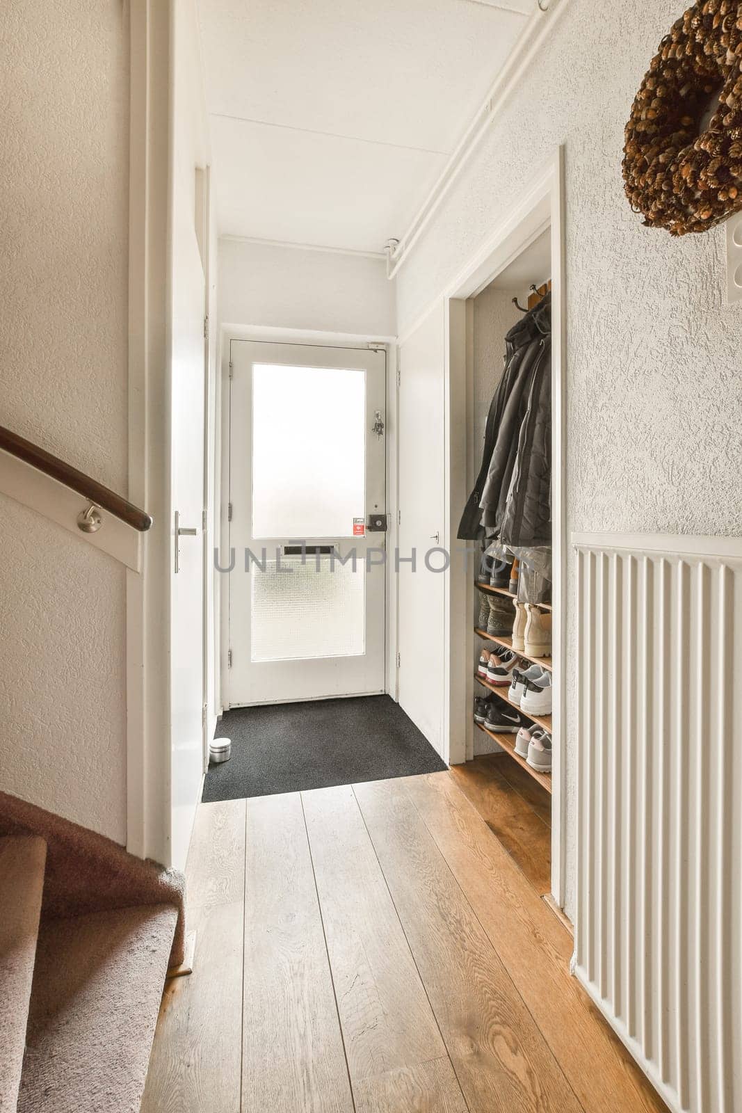 a hallway in a house with wood floors and white trim on the walls there is a coat rack hanging over the door