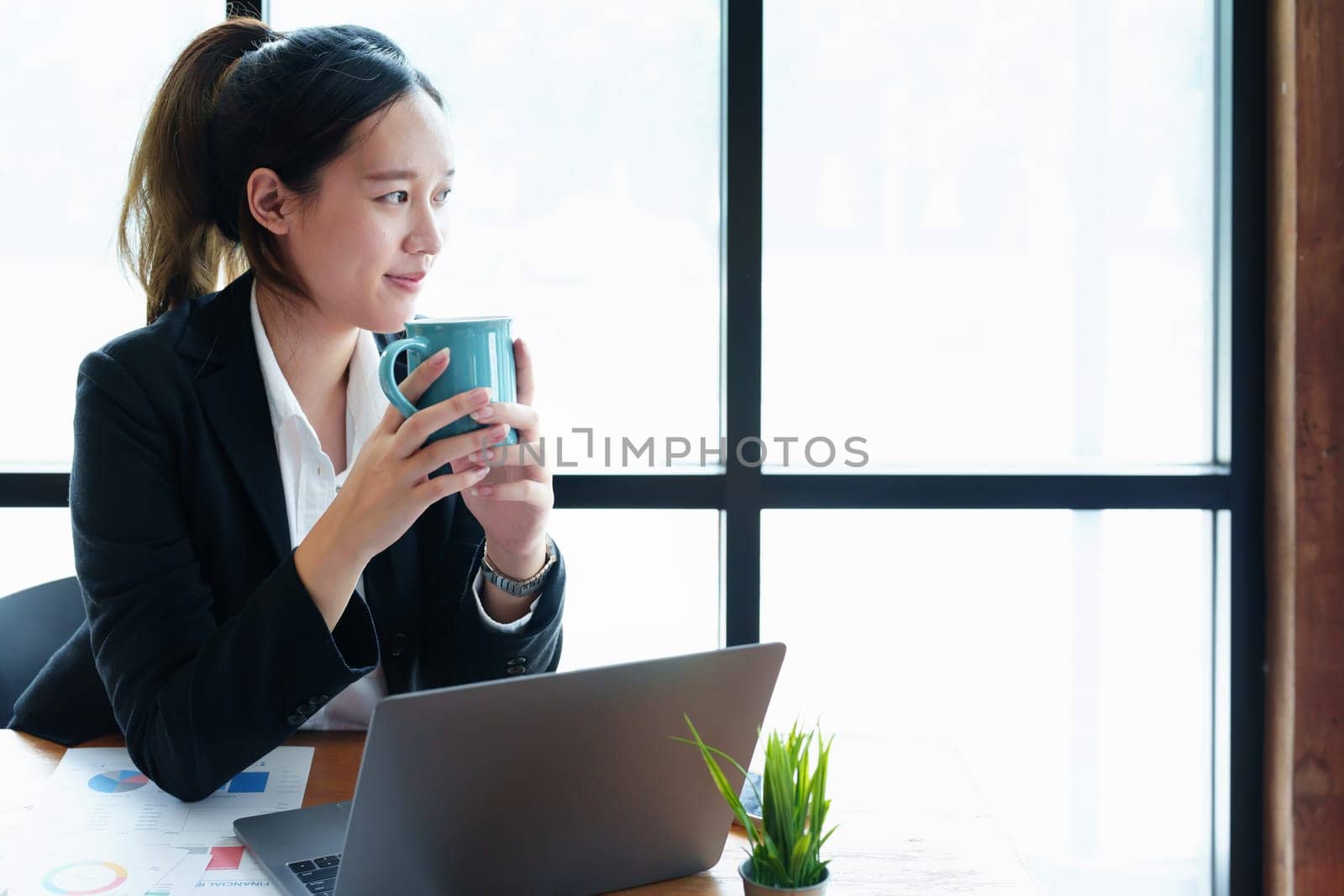 Portrait of a young woman drinking coffee while using a computer.