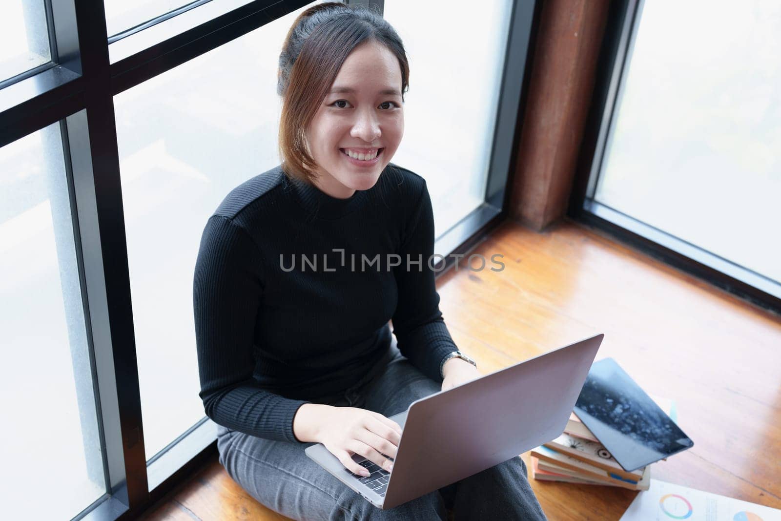 Portrait of an Asian woman using a computer to study online and drinking coffee while video conference.