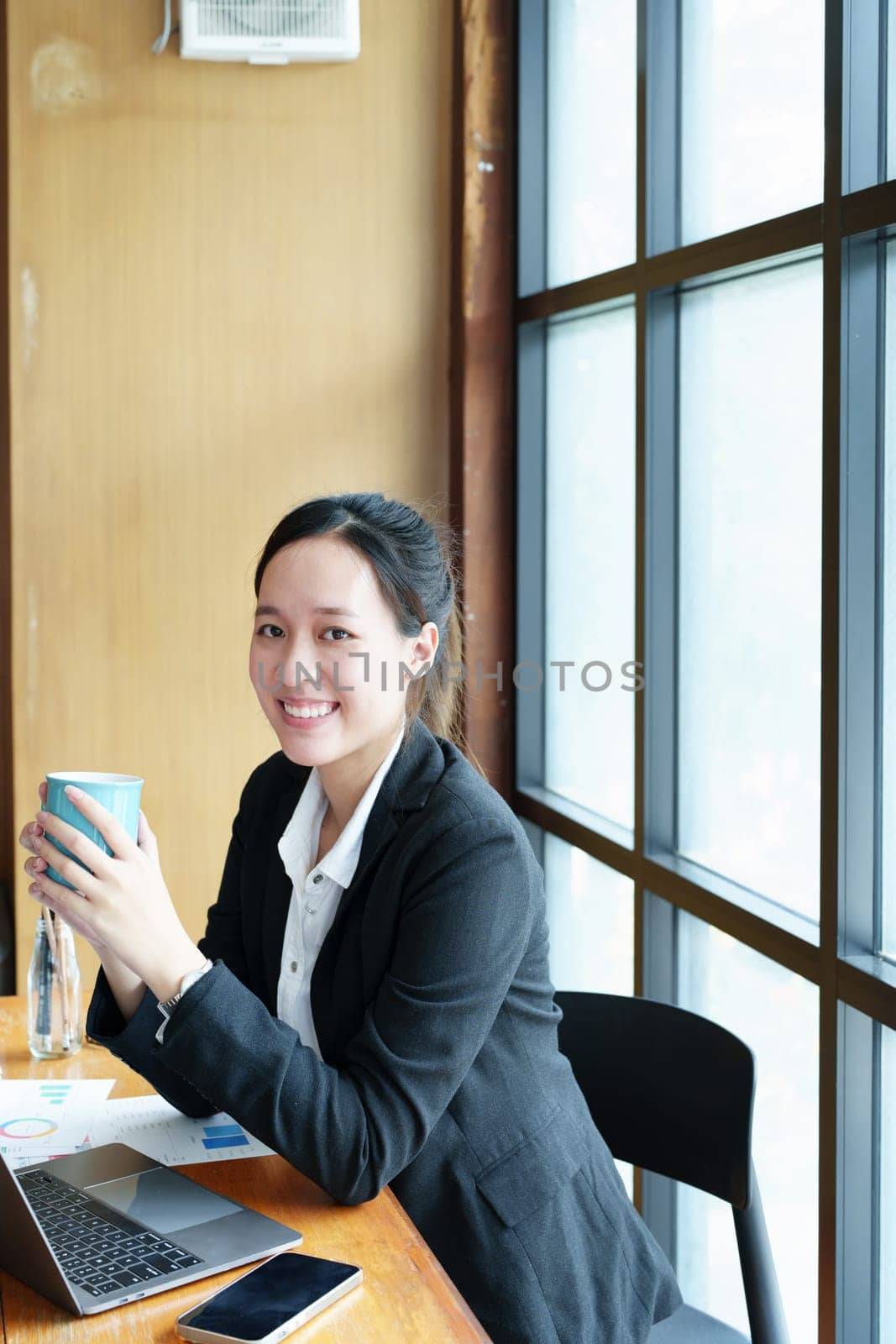 Portrait of a young woman drinking coffee while using a computer by Manastrong