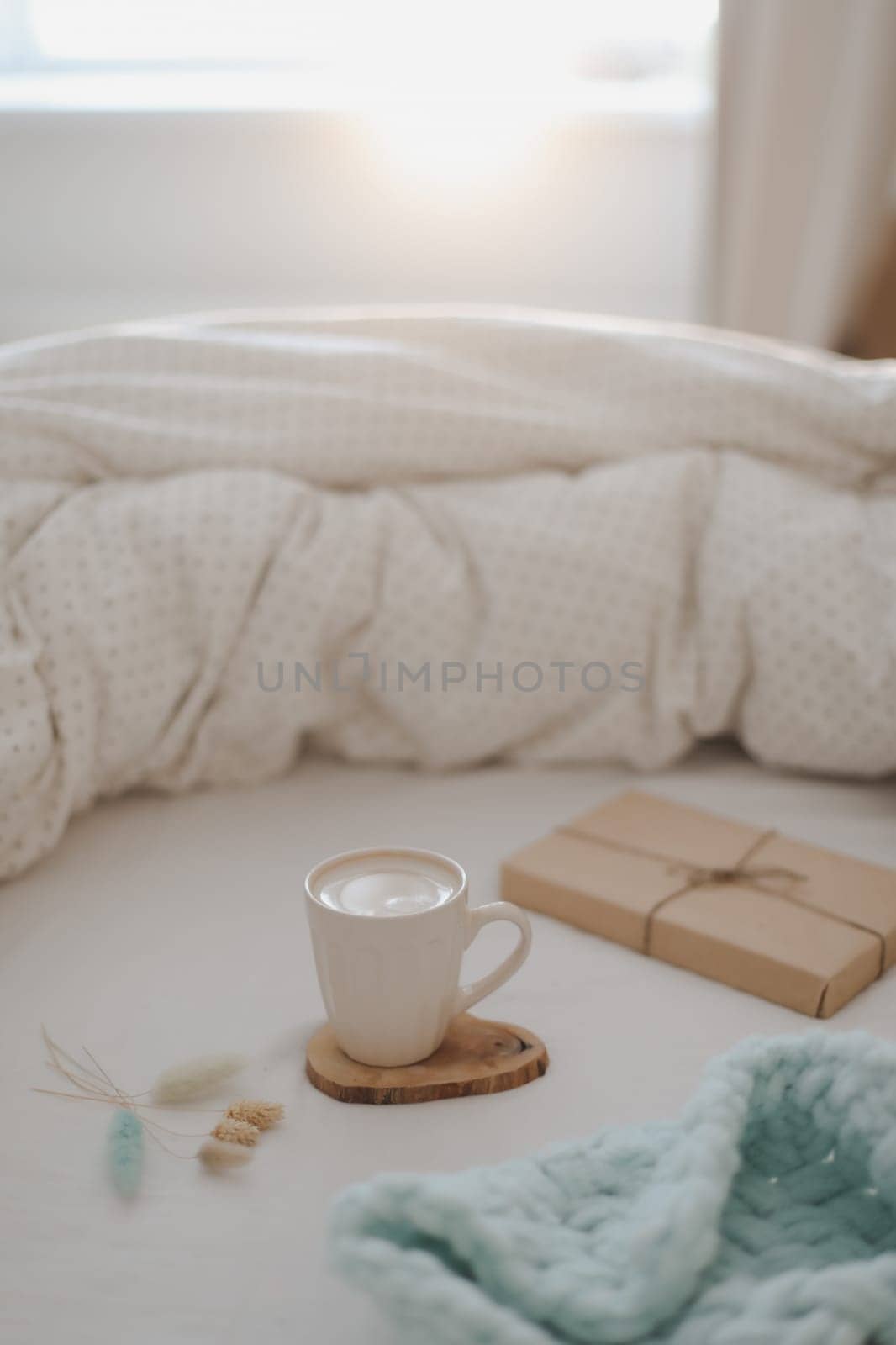 Light cozy bedroom, Coffee cup and gift or book on the bed. Good morning