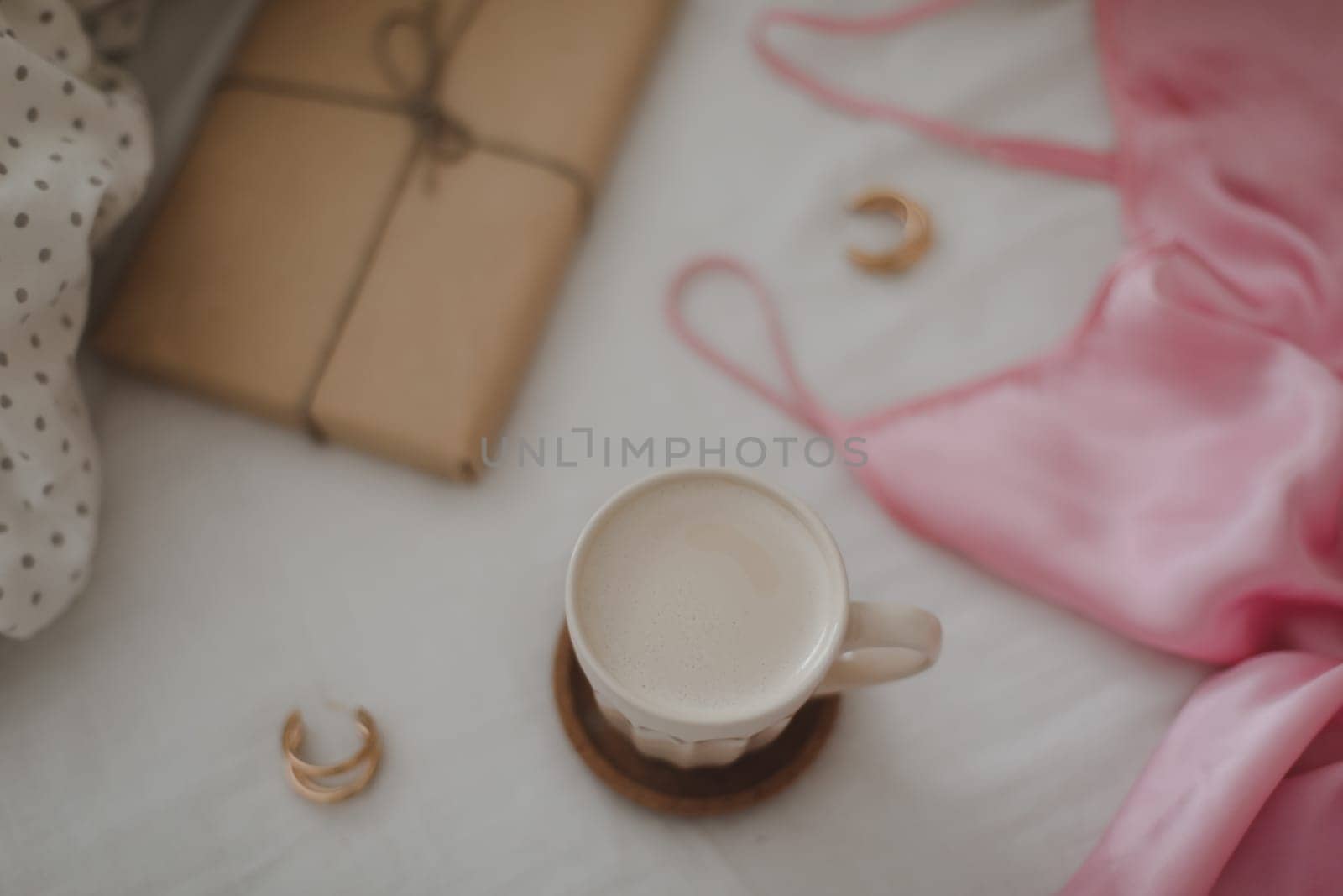 Light cozy bedroom, Coffee cup and gift or book on the bed. Good morning