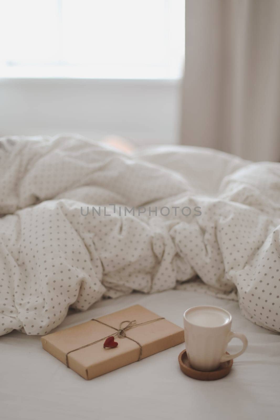 Light cozy bedroom, Coffee cup and gift or book on the bed. Good morning