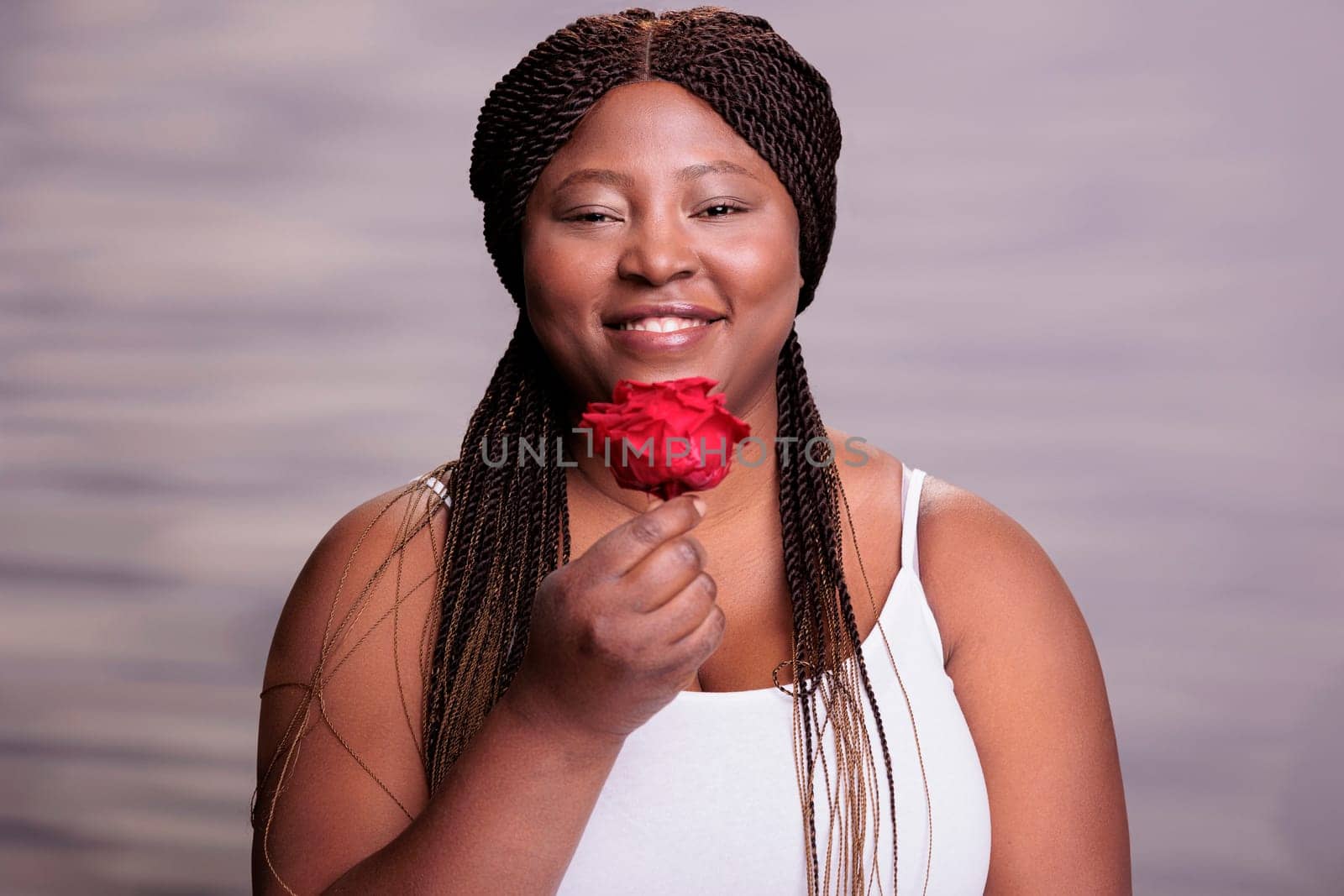 African american woman holding red rose love symbol portrait. Body positive smiling happy lady with flower showing beauty, passion and romance concept and looking at camera